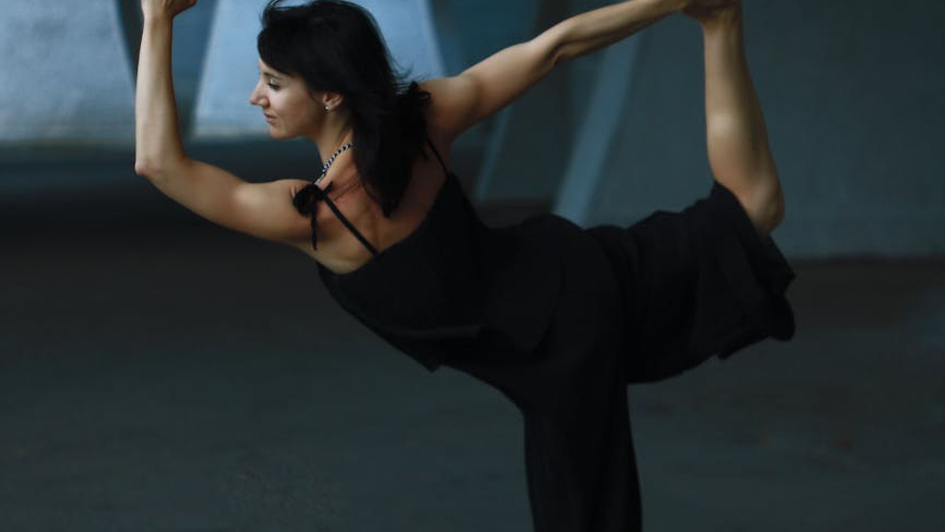 Silhouette of a woman in a graceful yoga pose against a dark, serene background.